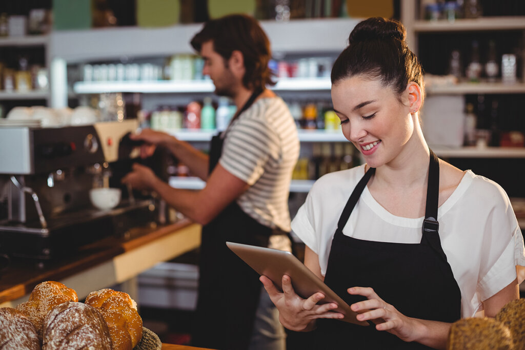 Une serveuse de café tient une tablette à la main.