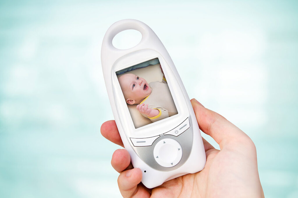 femme tenant un babyphone avec l'image du bébé à l'écran