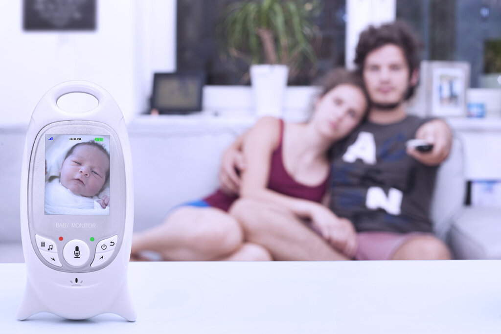 jeune couple assis sur canapé avec babyphone à l'avant