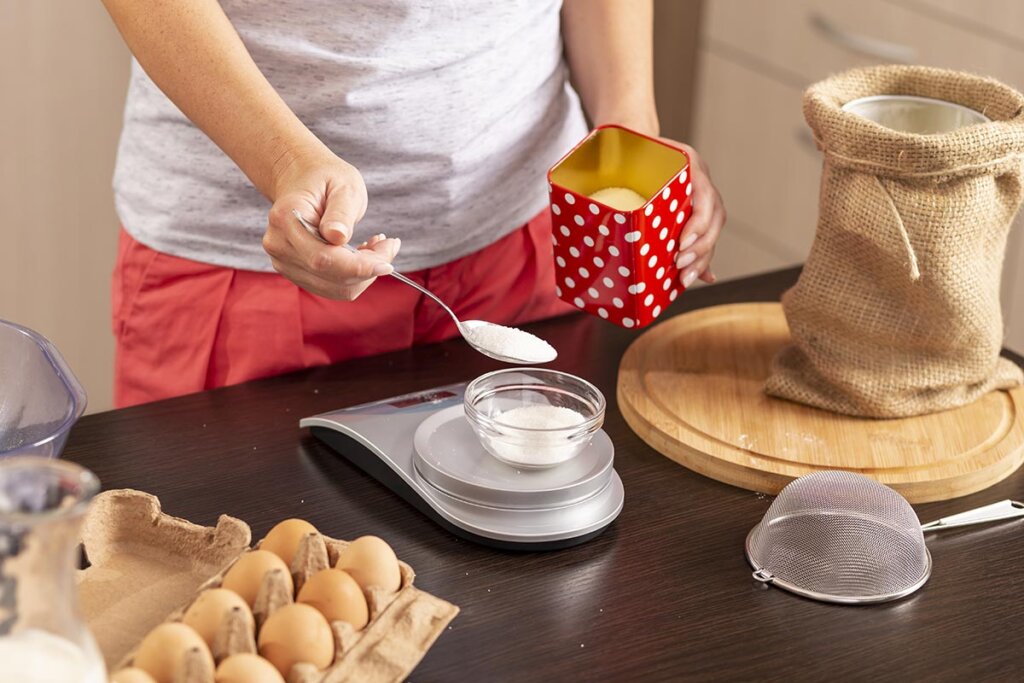 Une femme mesure du sucre dans la cuisine