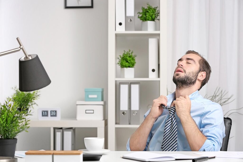 Un homme est assis au bureau en sueur