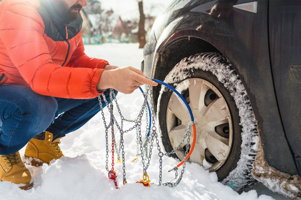 un homme met des chaînes à neige