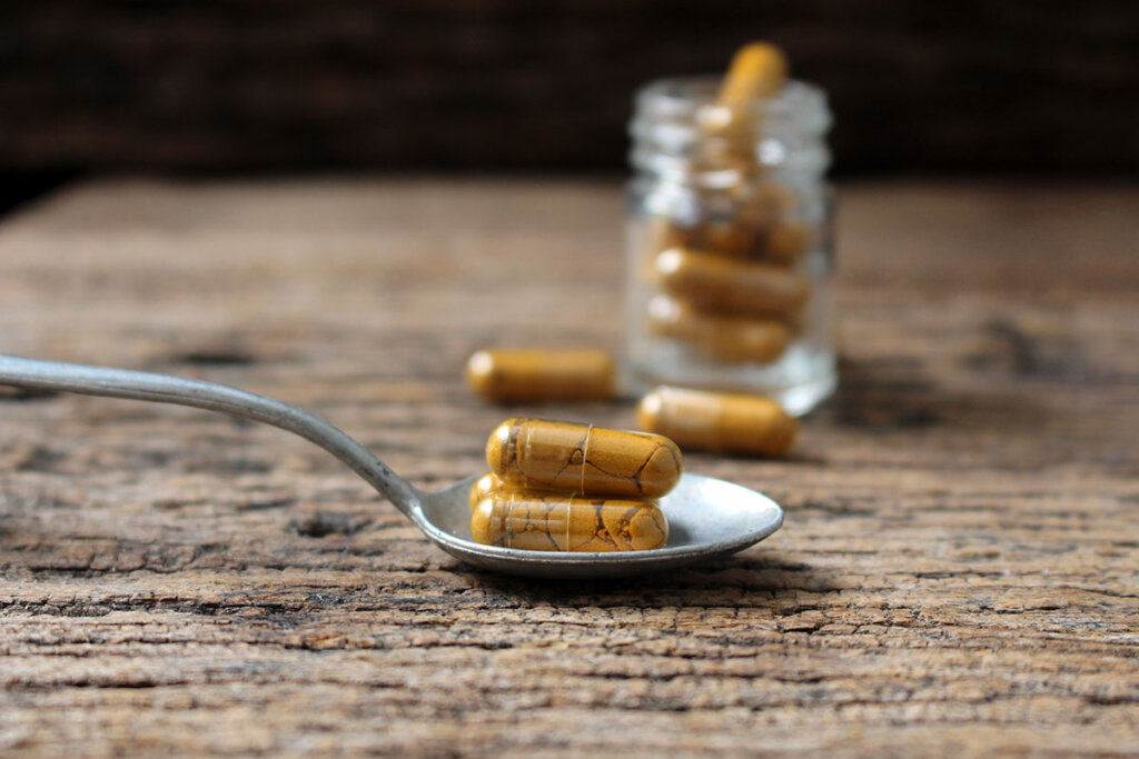 capsules de curcuma sur une cuillèrev